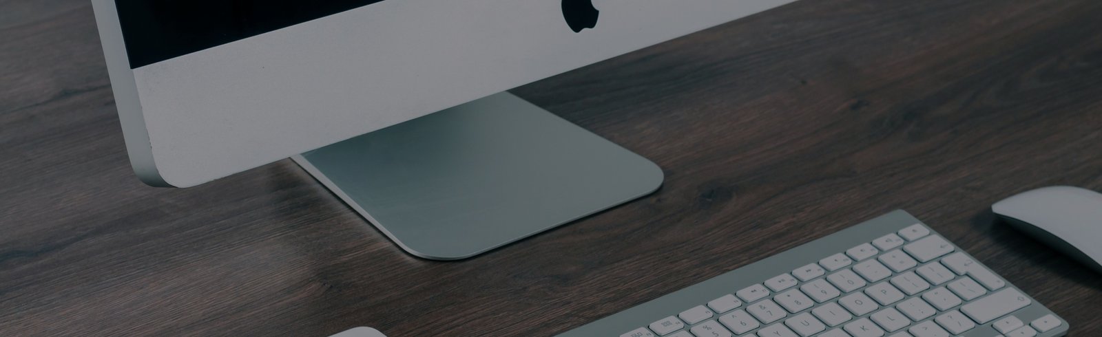 iMac computer and keyboard on a wooden desk, representing online booking and customer support for Local Cleaning Services.