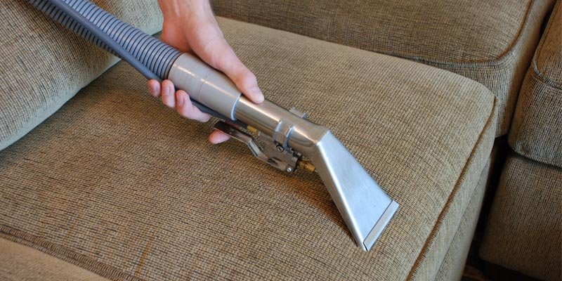 Hand holding upholstery cleaning tool on a sofa, demonstrating professional steam cleaning for furniture in Melbourne.