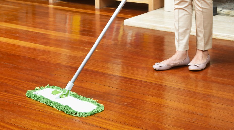 Person using a mop on polished vinyl floor, highlighting professional cleaning techniques for vinyl flooring maintenance.