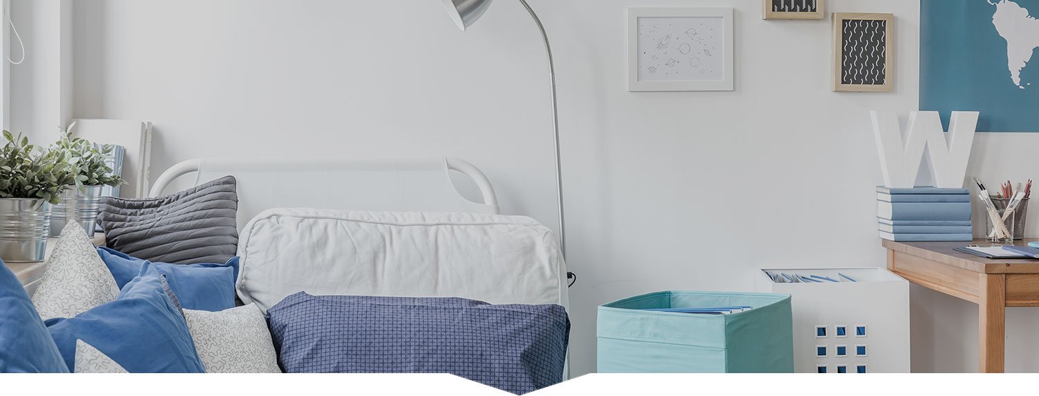 Cozy living room with a white couch adorned with blue cushions, a floor lamp, and a wooden table featuring decorative items, highlighting a clean and organized space ideal for house cleaning services.